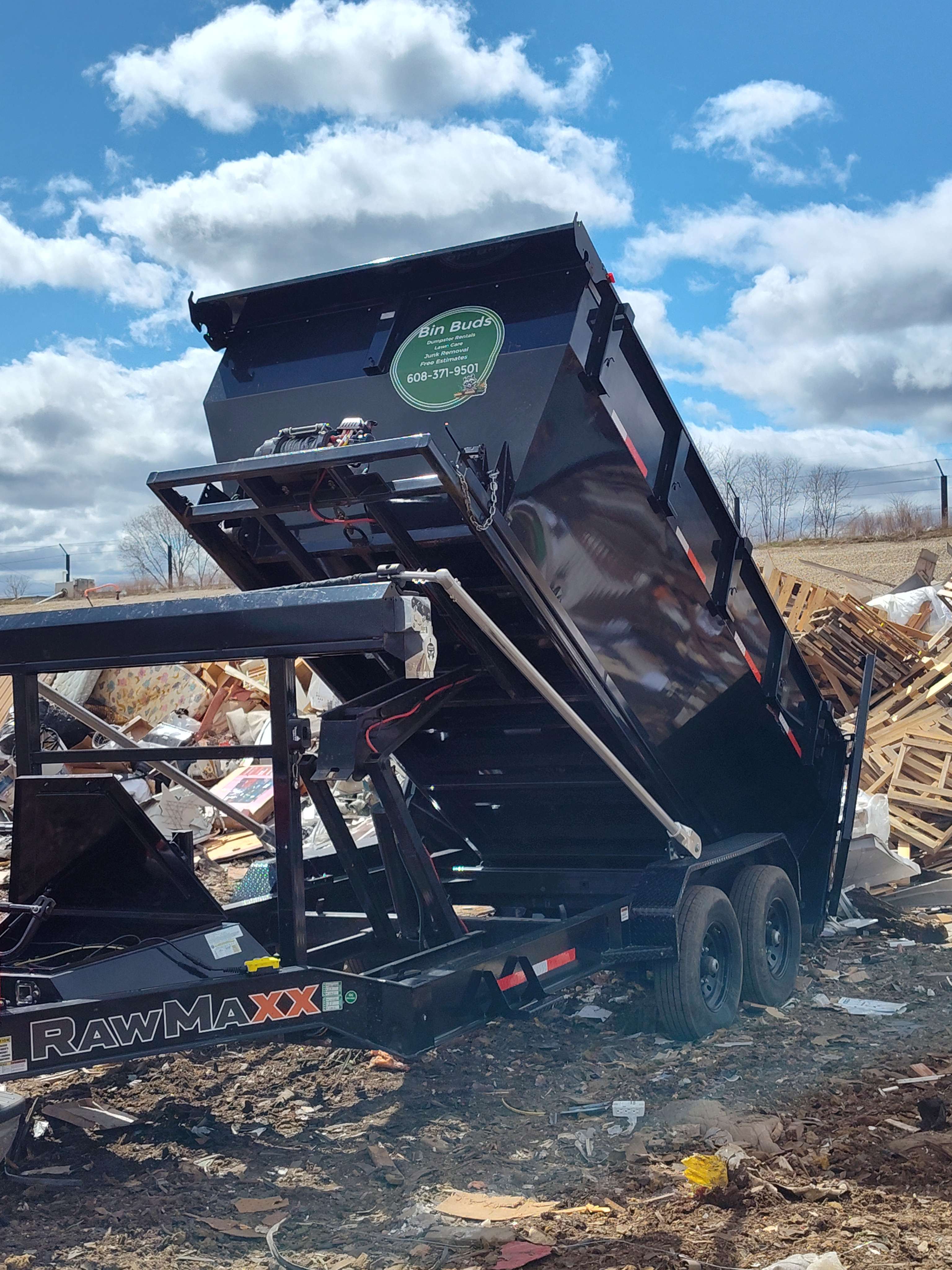 Black dump trailer with Bin Buds logo at construction waste site